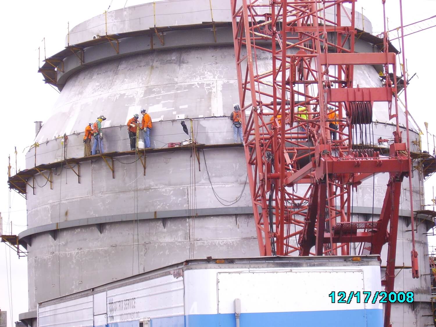 Construction workers standing on the exterior of large structure